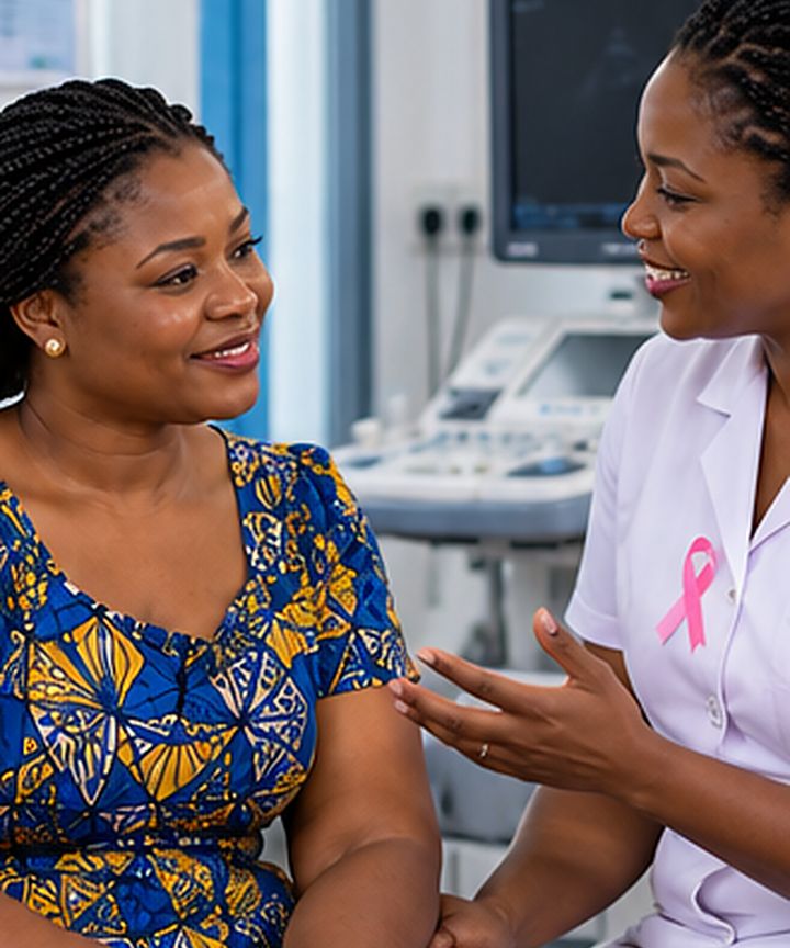 Une patiente souriante en consultation avec une sage-femme portant un ruban rose